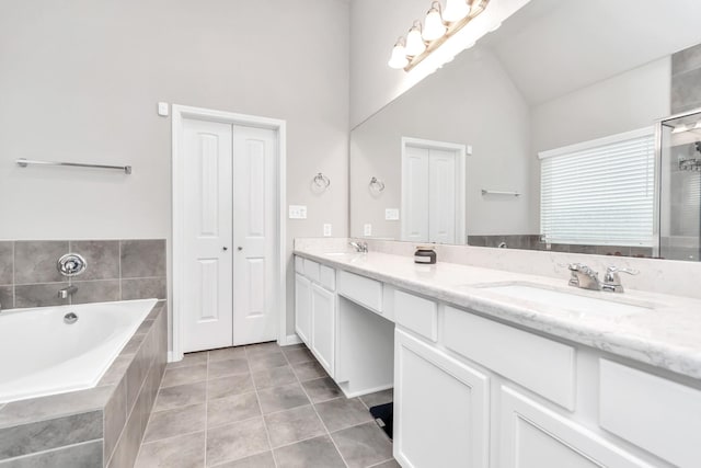 bathroom featuring tile patterned flooring, vanity, high vaulted ceiling, and tiled bath