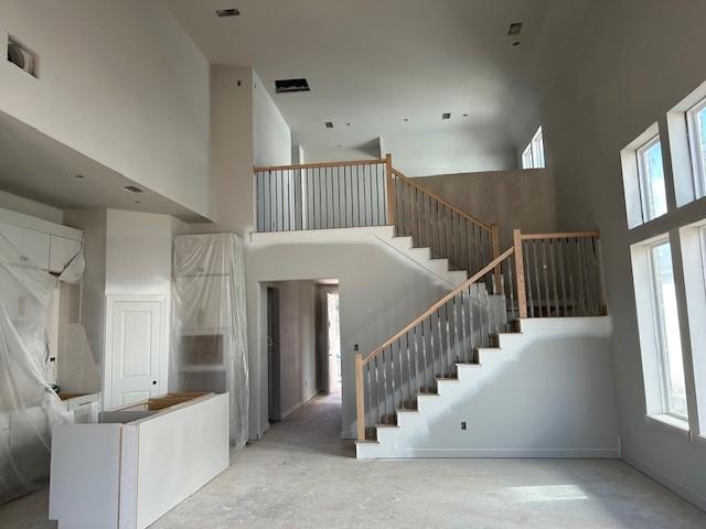 staircase with a towering ceiling and concrete floors