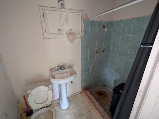 bathroom with tiled shower, tile patterned flooring, and toilet