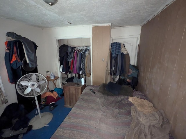 bedroom featuring wood walls, concrete flooring, and a closet