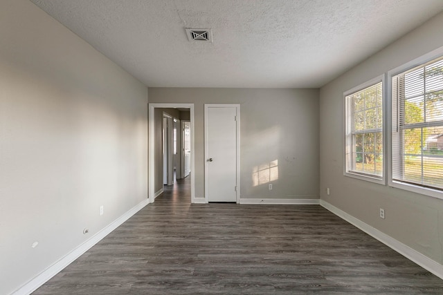 unfurnished room with a textured ceiling and dark wood-type flooring