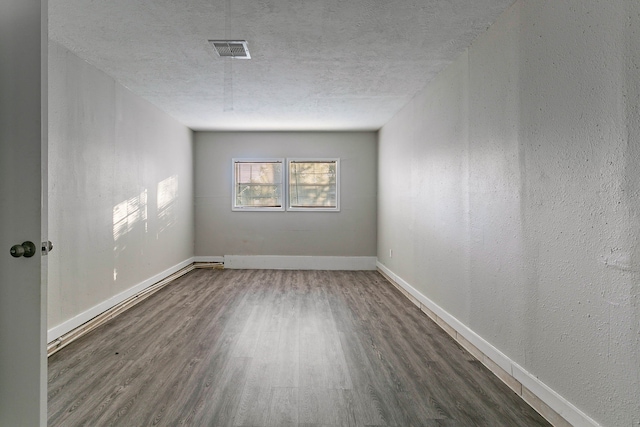 spare room featuring dark wood-type flooring and a textured ceiling