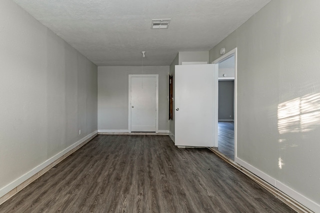 unfurnished room featuring a textured ceiling and dark wood-type flooring