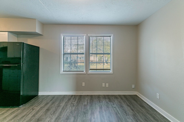 kitchen with black fridge, wood-type flooring, and a textured ceiling