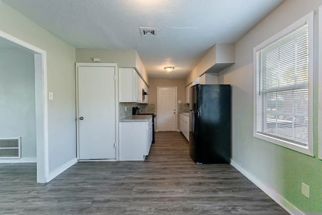 kitchen featuring black refrigerator, dark hardwood / wood-style flooring, white cabinetry, and a healthy amount of sunlight