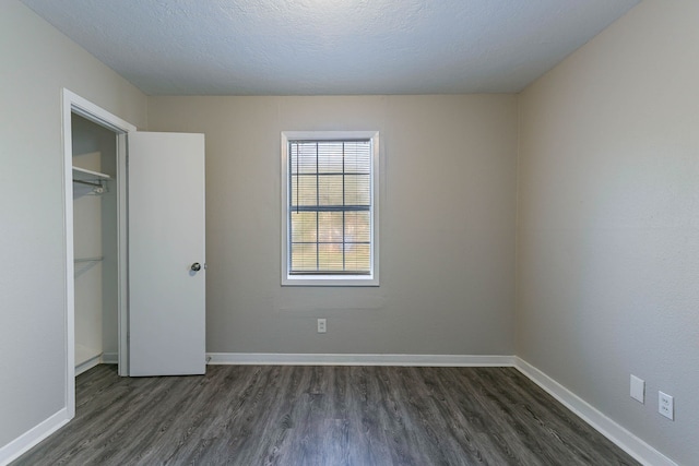 unfurnished bedroom with dark hardwood / wood-style floors, a textured ceiling, and a closet