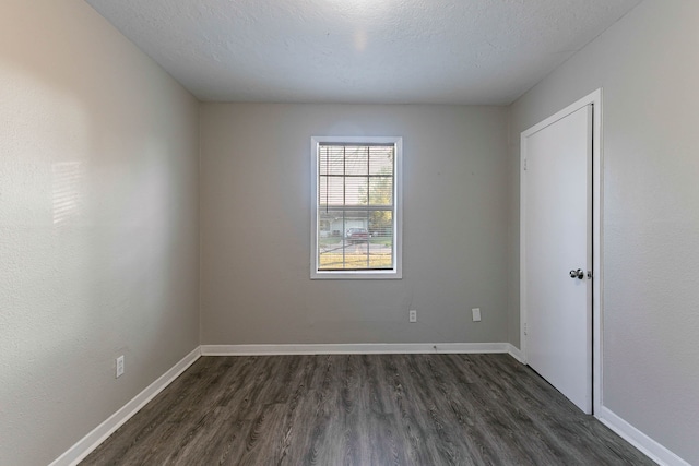 empty room with dark wood-type flooring and a textured ceiling