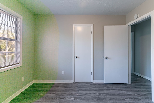 unfurnished bedroom featuring a textured ceiling and dark hardwood / wood-style floors