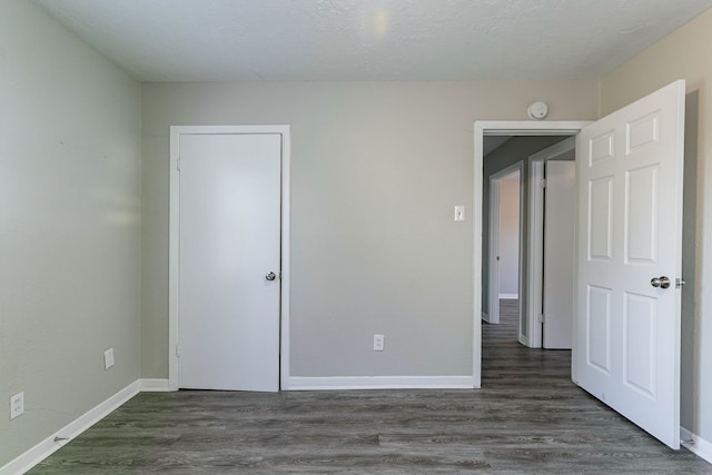 unfurnished bedroom with a textured ceiling and dark wood-type flooring