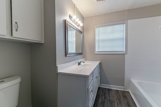 bathroom with hardwood / wood-style floors, vanity, toilet, and a textured ceiling