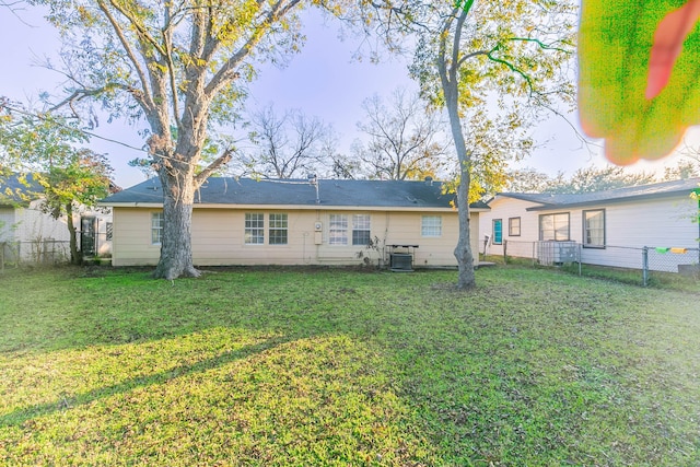 rear view of property featuring a yard and central AC unit