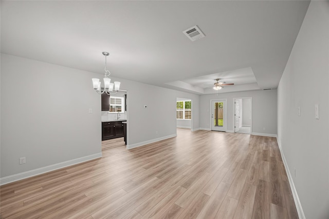 10318 Prairie Dunes Ln, Cleveland, TX 77327 - unfurnished living room with a tray ceiling, a chandelier, light wood finished floors, ceiling fan, and baseboards