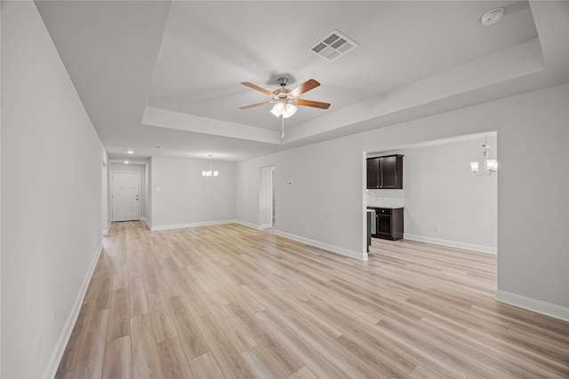 10318 Prairie Dunes Ln, Cleveland, TX 77327 - unfurnished living room with a chandelier, a tray ceiling, a ceiling fan, and light wood-type flooring