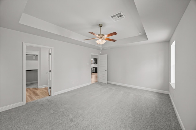 10318 Prairie Dunes Ln, Cleveland, TX 77327 - unfurnished bedroom featuring a raised ceiling, carpet, baseboards, a ceiling fan, and a walk in closet