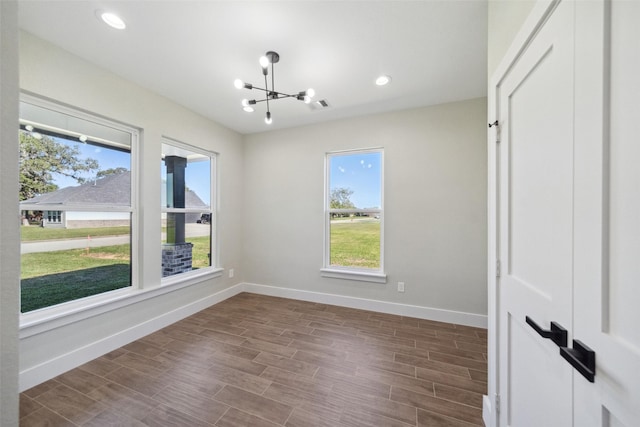 empty room featuring a chandelier, hardwood / wood-style floors, and plenty of natural light