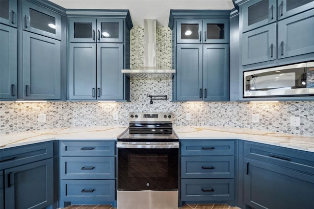 kitchen featuring light stone countertops, wall chimney range hood, appliances with stainless steel finishes, and tasteful backsplash