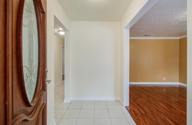 hall with a textured ceiling, light wood-type flooring, and ornamental molding