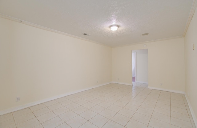 empty room featuring crown molding, light tile patterned floors, and a textured ceiling