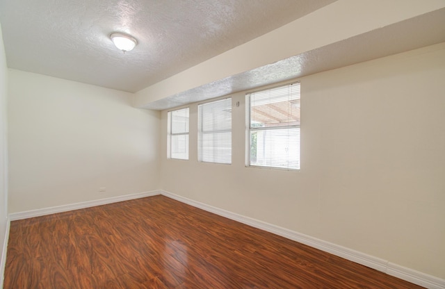 unfurnished room featuring a textured ceiling and dark hardwood / wood-style flooring