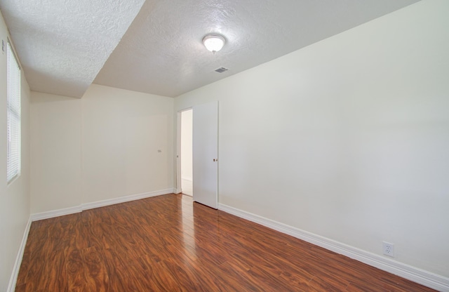 unfurnished room with dark hardwood / wood-style flooring and a textured ceiling