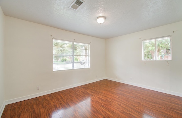 spare room with hardwood / wood-style flooring, a healthy amount of sunlight, and a textured ceiling