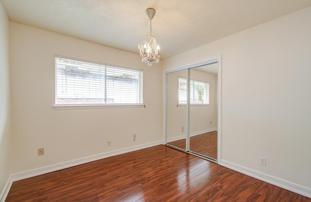 unfurnished bedroom with hardwood / wood-style flooring, a chandelier, and a closet