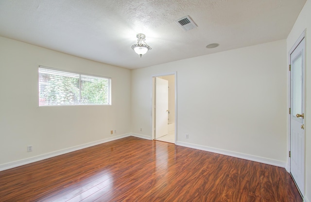 spare room with a textured ceiling and dark hardwood / wood-style floors