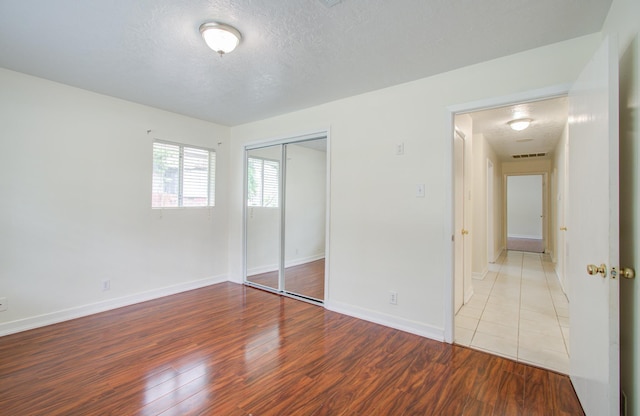 unfurnished bedroom with light hardwood / wood-style floors, a textured ceiling, and a closet