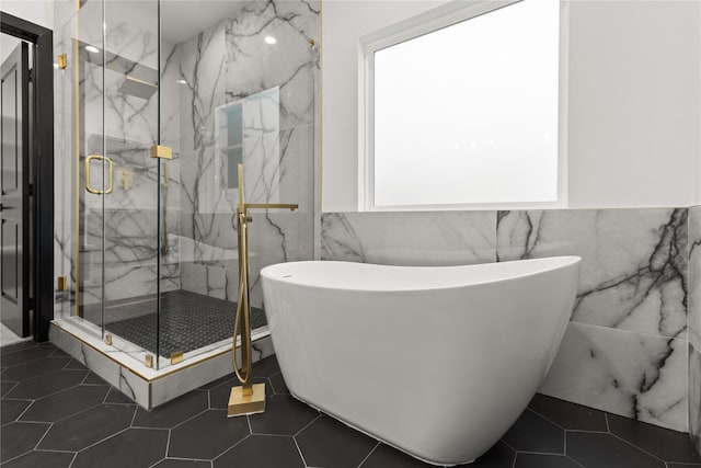 bathroom with a wealth of natural light, tile patterned flooring, independent shower and bath, and tile walls