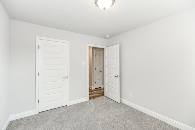 unfurnished bedroom with light colored carpet and a closet