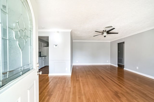 spare room with a textured ceiling, ceiling fan, wood-type flooring, and crown molding