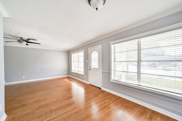 foyer entrance with a textured ceiling, light wood-type flooring, ceiling fan, and crown molding