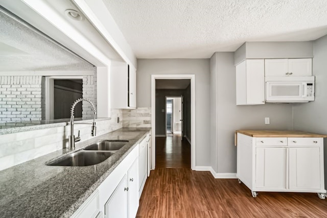 kitchen featuring sink, dark hardwood / wood-style flooring, a textured ceiling, white appliances, and white cabinets