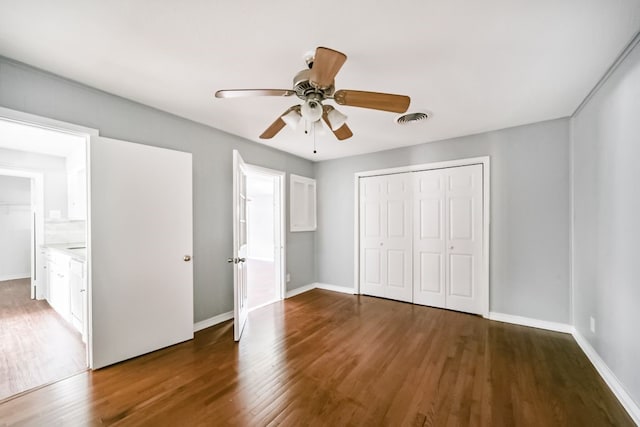 unfurnished bedroom featuring connected bathroom, ceiling fan, a closet, and dark hardwood / wood-style floors