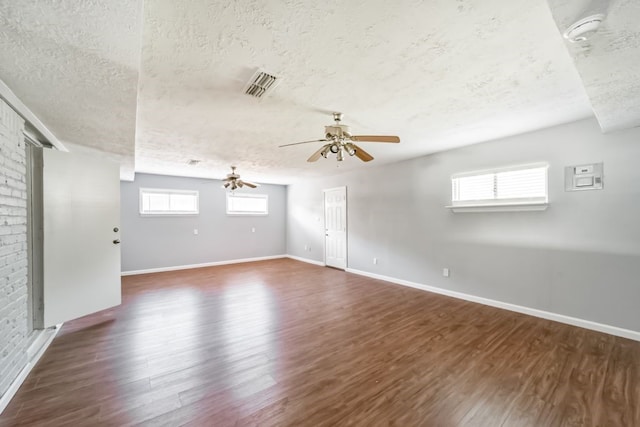 unfurnished room featuring dark hardwood / wood-style floors, ceiling fan, a textured ceiling, and a wealth of natural light