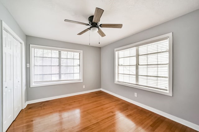 unfurnished bedroom with hardwood / wood-style floors, ceiling fan, and a closet