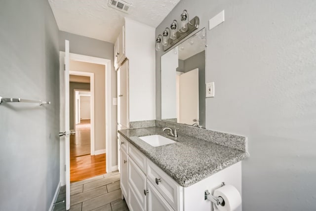 bathroom featuring a textured ceiling, vanity, and hardwood / wood-style flooring