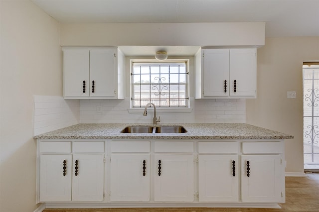 kitchen with white cabinets, sink, light tile patterned floors, tasteful backsplash, and light stone counters