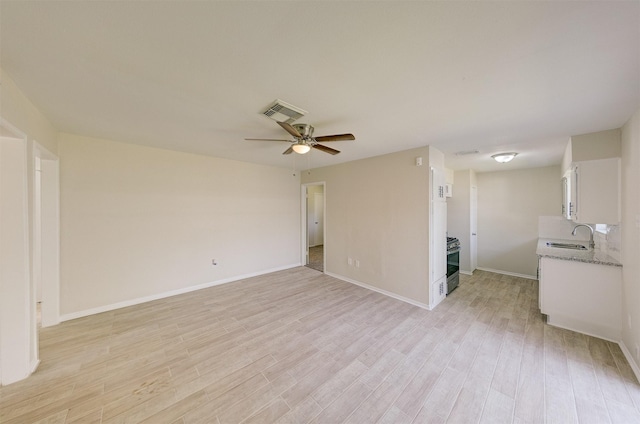 unfurnished living room with ceiling fan, light wood-type flooring, and sink