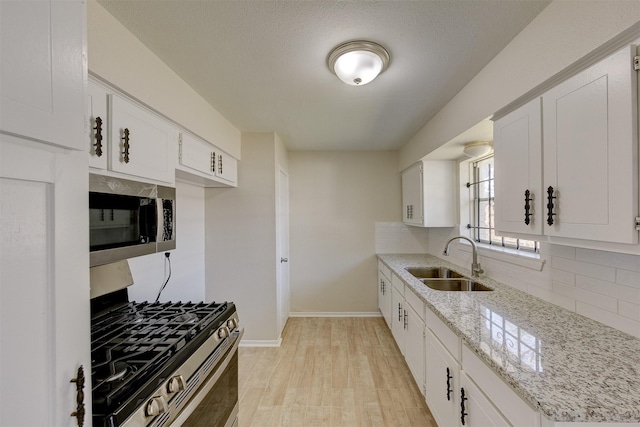 kitchen with white cabinets, light wood-type flooring, sink, and appliances with stainless steel finishes