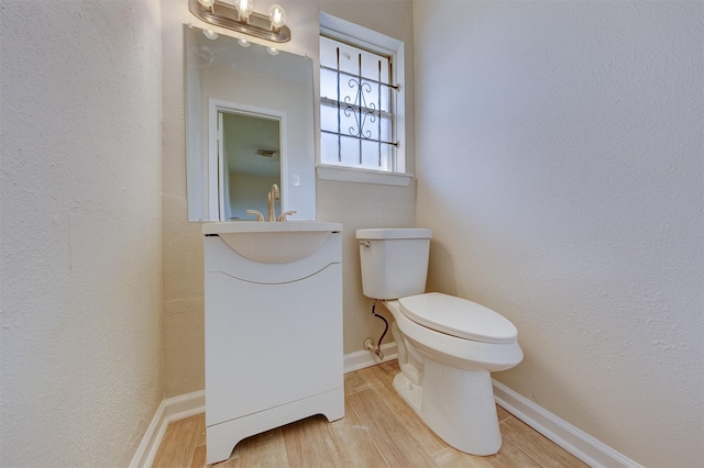 bathroom featuring toilet, vanity, and hardwood / wood-style flooring