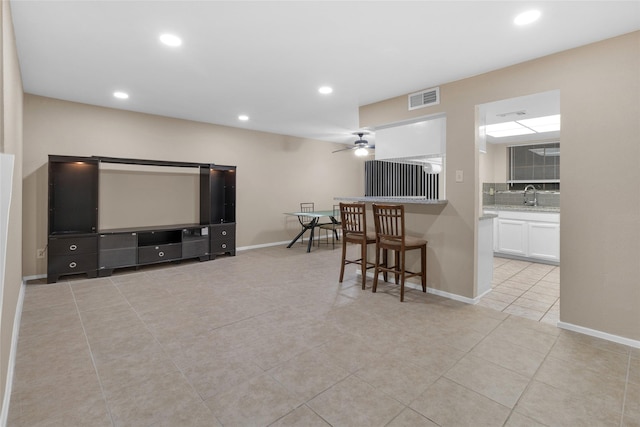 tiled living room featuring ceiling fan and sink