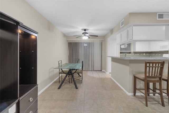 tiled dining space with ceiling fan