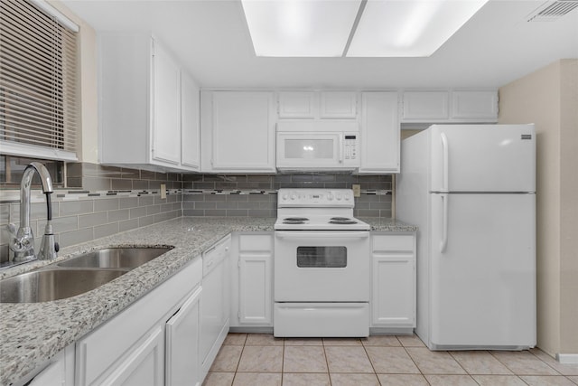 kitchen with white appliances, white cabinets, sink, light tile patterned floors, and tasteful backsplash