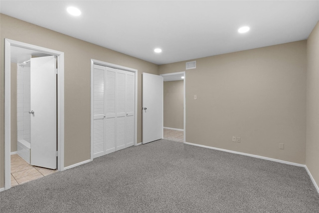 unfurnished bedroom with ensuite bathroom, light colored carpet, and a closet