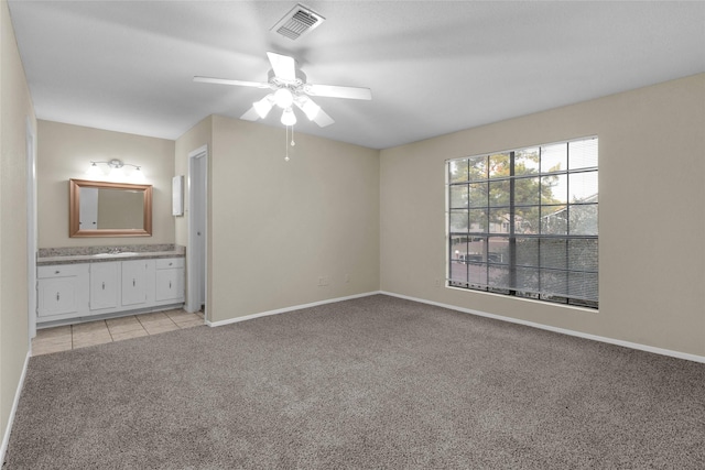 unfurnished bedroom with ceiling fan, light colored carpet, and connected bathroom