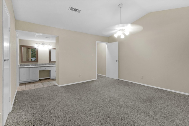 unfurnished bedroom featuring light carpet, built in desk, and vaulted ceiling