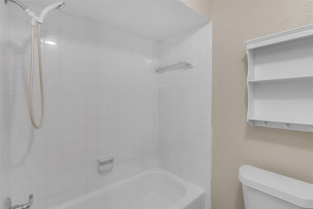 bathroom with toilet and tiled shower / bath