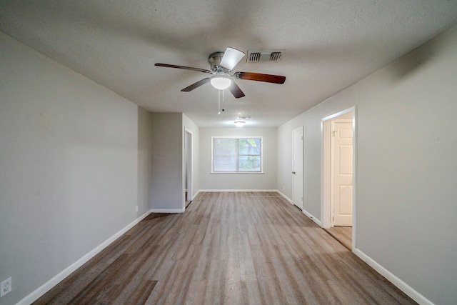 empty room featuring light wood-type flooring, a textured ceiling, and ceiling fan