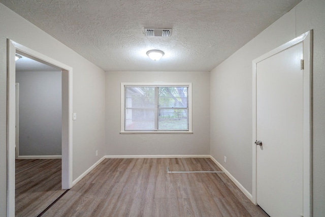 unfurnished room featuring light hardwood / wood-style floors and a textured ceiling